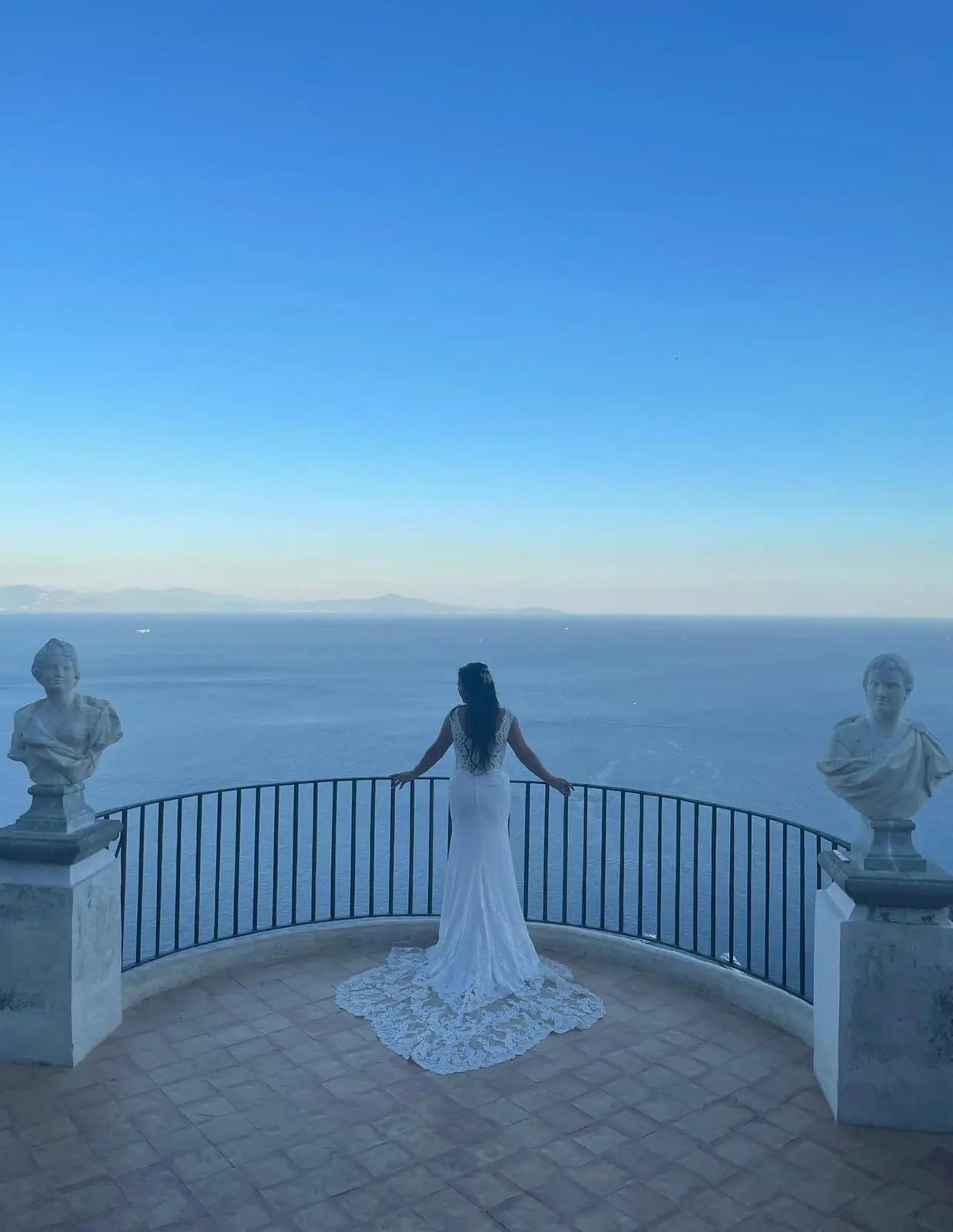 The bride on the Terrace of Infinity at Villa Cimbrone, looking out between the marble busts toward the coast