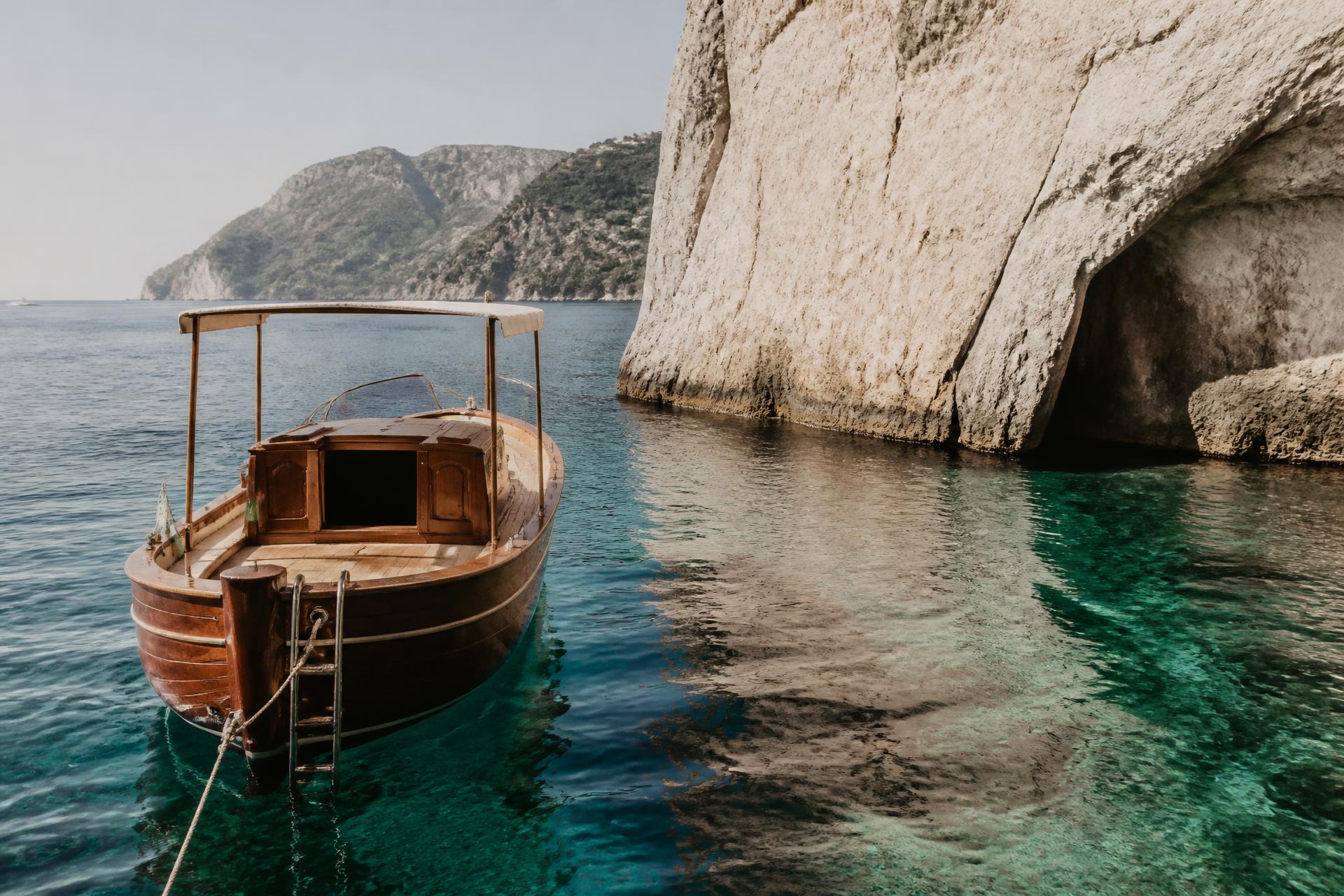 A private wooden boat anchored in turquoise water along the Amalfi Coast